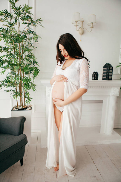 Menina grávida bonita em um vestido branco no interior - Foto, Imagem