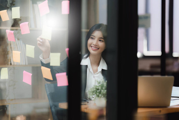 Krásná asijská podnikatelka pracující s lepkavým vzkazem v kanceláři. Finanční analýza a daňová koncepce. - Fotografie, Obrázek