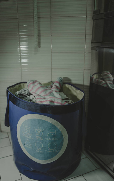 Сумка з символами того, як прати одяг, заповнений зверху і готовий покласти в пральну машину
 - Фото, зображення