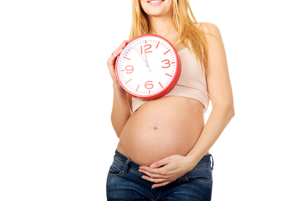 Pregnant woman with a clock - Фото, изображение