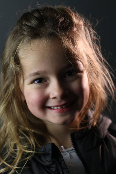 Retrato de una hermosa joven sonriendo sobre un fondo gris - Foto, Imagen
