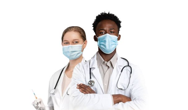 Geneeskunde en gezondheidszorg. Mannelijke en vrouwelijke arts dragen maskers en uniform staan geïsoleerd over witte achtergrond, multi-etnische medische werkers kijken naar camera, collage, kopieerruimte - Foto, afbeelding