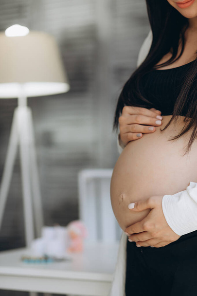 Pienet kengät syntymättömälle lapselle raskaana olevan naisen vatsassa - Valokuva, kuva