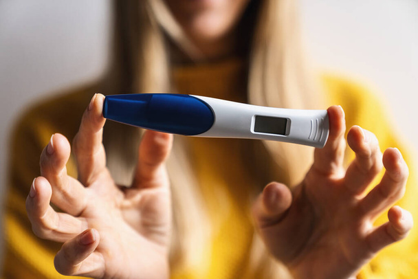 Close-up van een vrouw te houden positieve zwangerschap snelle plastic test die bevestigen dat ze zwanger is. Nieuw leven, vrouwelijke gezondheid, gelukkige veranderingen en bevruchting concept beeld kopieer ruimte of tekst - Foto, afbeelding
