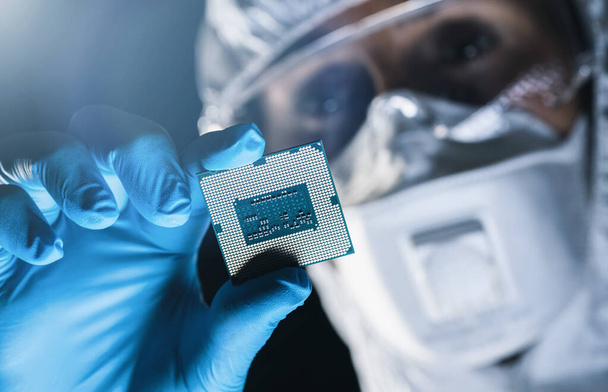 Ультрасовременная мануфактурная фабрика, в стерильной коверле держит микрочип с глотками и исследует его - Фото, изображение