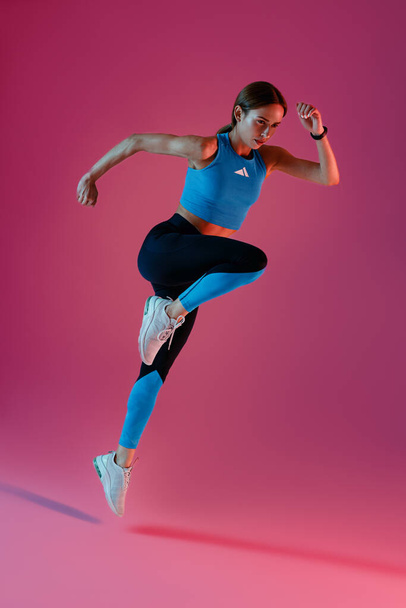 Mujer corriendo en Mid-Air haciendo ejercicio durante el entrenamiento cardiovascular en el fondo del estudio. Foto de alta calidad - Foto, imagen