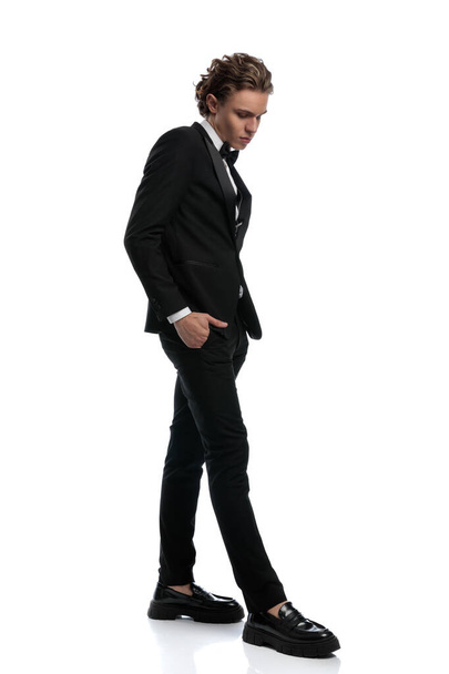 young businessman walking with a dramatic stance, wearing a formal outfit against white studio background - Foto, Bild