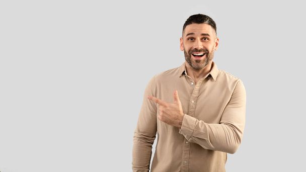 Cool special offer. Portrait of excited middle aged man pointing finger aside at copy space and looking at camera with excitement, standing over grey studio background, banner panorama - Φωτογραφία, εικόνα