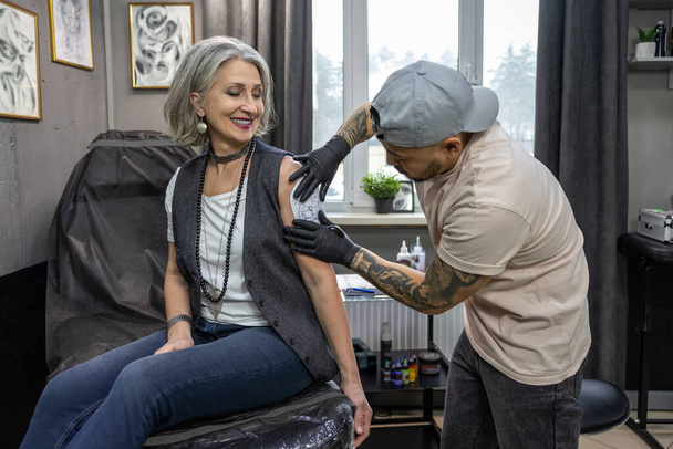 Tattoo sketch. Tattoo master applying a tattoo sketch on the womans shoulder - Zdjęcie, obraz