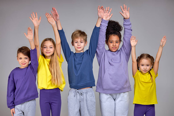 diverse happy children raising their hands, arms looking at camera close up portrait isolated grey background, happiness happy childhood - Foto, immagini