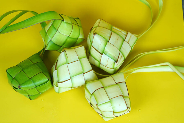 Hojas de palma Ketupat o tejidas para pasteles de arroz para celebrar Eid Mubarak en Indonesia. Aislado sobre fondo amarillo. - Foto, Imagen