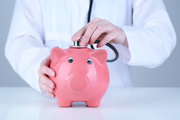 Doctor with pink piggy bank - 写真・画像