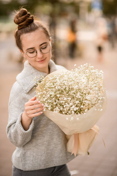 beautiful young woman with large bouquet of white gypsophila flowers in wrapping paper in the hands - Foto, Imagen