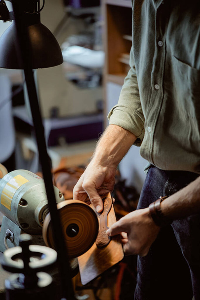 man using hand-crafted, high-quality burnisher at workplace. close up side view shot.Leather Craft - 写真・画像