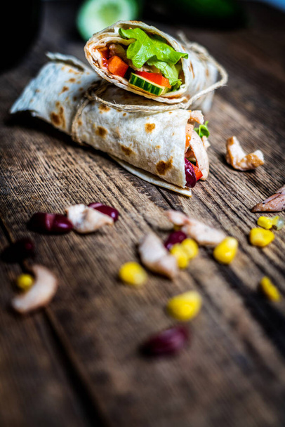 Traditional mexican tortilla wrap with chicken meat and vegetables on wood table - Fotografie, Obrázek