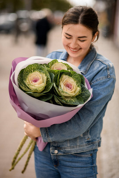 beautiful bouquet of ornamental cabbage brassica in wrapping paper in the hands of happy young woman - Valokuva, kuva