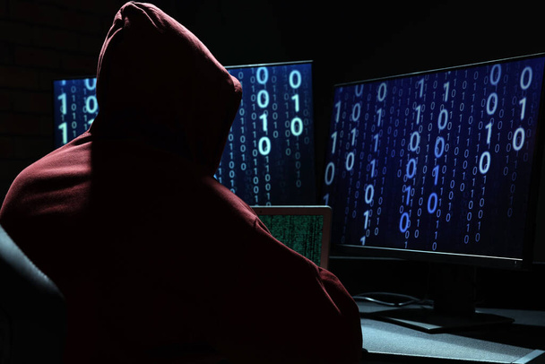Hacker werkt met computers in donkere kamer, achteraanzicht. Cyberaanval - Foto, afbeelding
