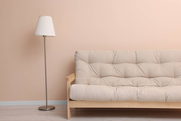 Comfortable sofa and stylish lamp near beige wall indoors - Zdjęcie, obraz
