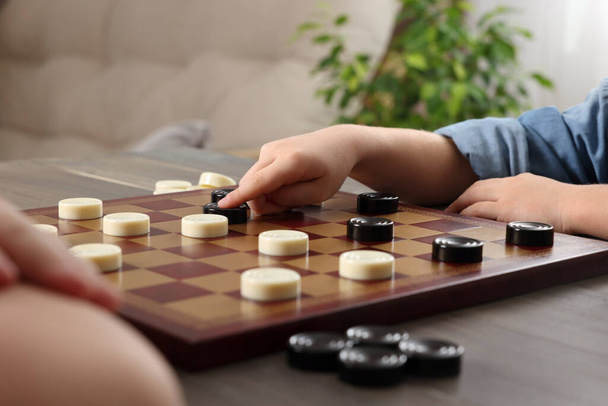 Children playing checkers at table in room, closeup - Foto, imagen