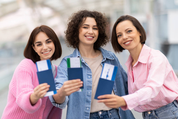 Three Happy Women Posing With Passports And Tickets In Hands At Airport, Cheerful Young Female Friends Showing Travel Documents At Camera While Standing At Terminal Hall, Enjoying Upcoming Trip - Foto, immagini