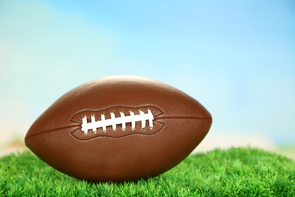 American football on field on green grass, on blue sky background - Valokuva, kuva