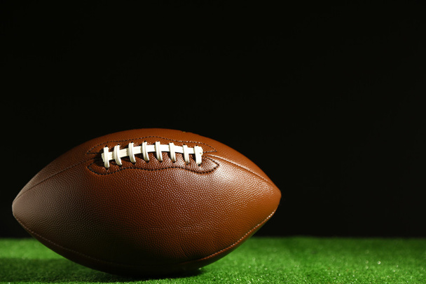 American football on green grass, on black background - Fotó, kép