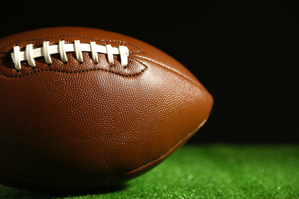 American football on green grass, on black background - Foto, imagen