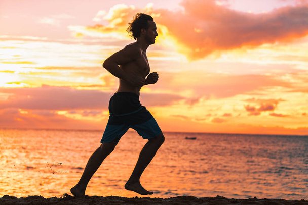 Running man jogging on beach silhouette. Male athlete runner training against sunset training cardio outdoors run. Travel vacation fitness sport. - 写真・画像
