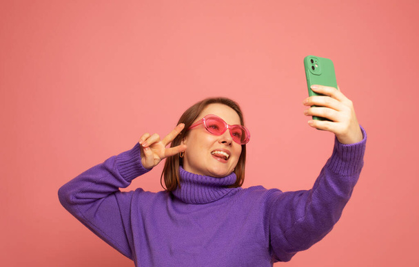 Image of cheerful curvy woman standing isolated over pink background wall talking by mobile phone. - Фото, зображення