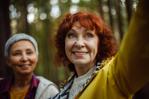 Multiracial elderly women having fun during trekking day in to the wood and make selfie with smartphone. Lifestyle concept. - Fotoğraf, Görsel
