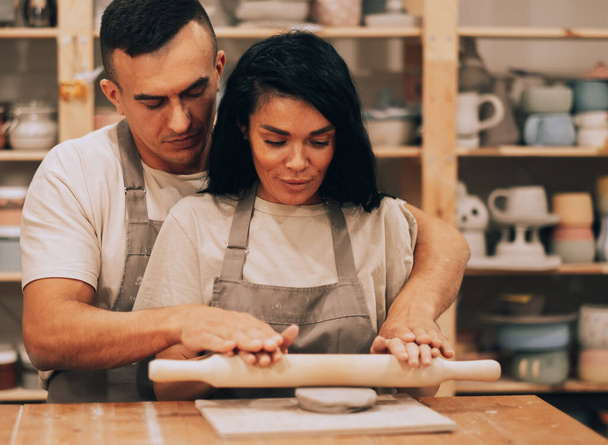 A young couple works in a pottery workshop. The concept of hobbies, lifestyle and relationships. - Foto, Imagem