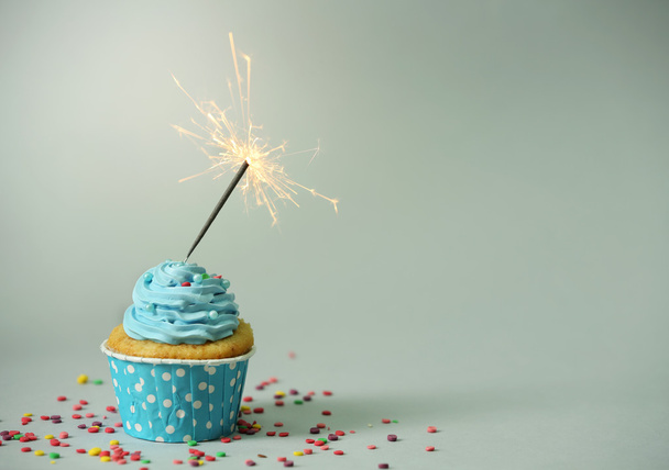 Cupcake with sparkler on grey background - Foto, Bild