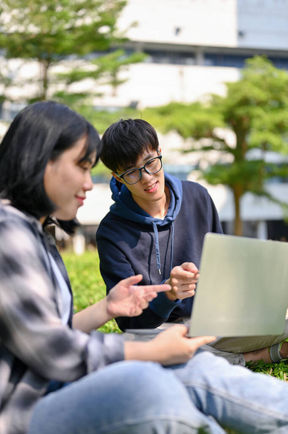 Muotokuva, fiksu nuori aasialainen mies college opiskelija tutorointi matematiikkaa hänen naispuolinen ystävä tai työskentelevät koulutyötä yhdessä yliopiston puistossa. - Valokuva, kuva
