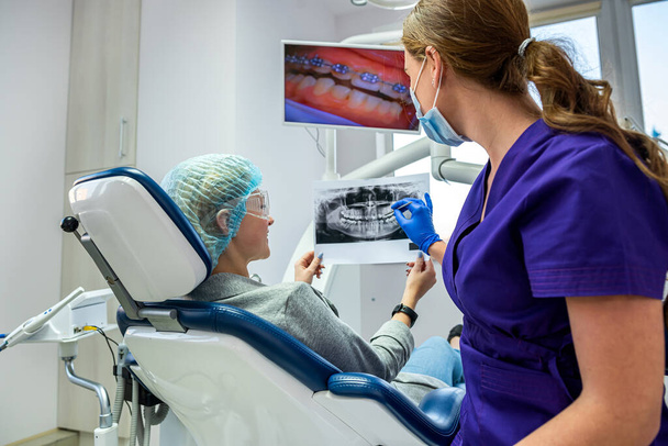 Un dentista profesional muestra las imágenes del paciente de su mandíbula y dientes. El concepto de imágenes de la mandíbula y los dientes en el dentista - Foto, imagen