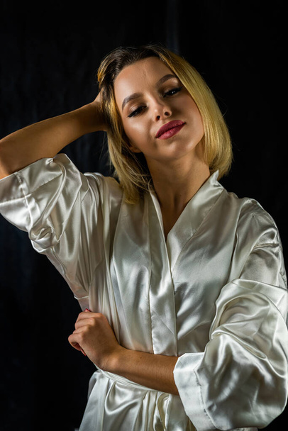 pretty young woman in a light silk robe showing comfort and joy. isolated on a plain background. concept of portrait photography. girl - Foto, Bild