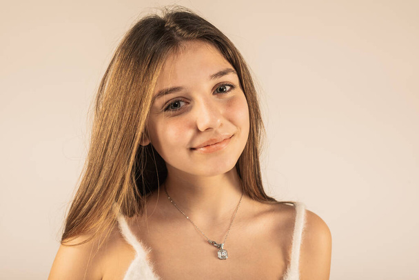 Joven chica hermosa con la piel limpia usando top lanudo y collar aislado en fondo beige - Foto, Imagen