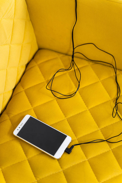 Charging a phone on sofa - 写真・画像