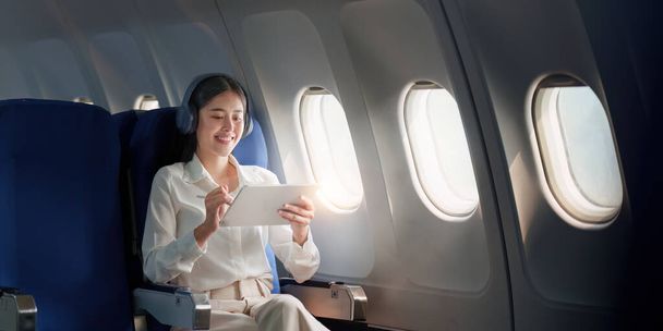 Hermosa mujer de negocios asiática que trabaja con tableta digital en avión. trabajo, viajes, concepto de negocio. - Foto, imagen