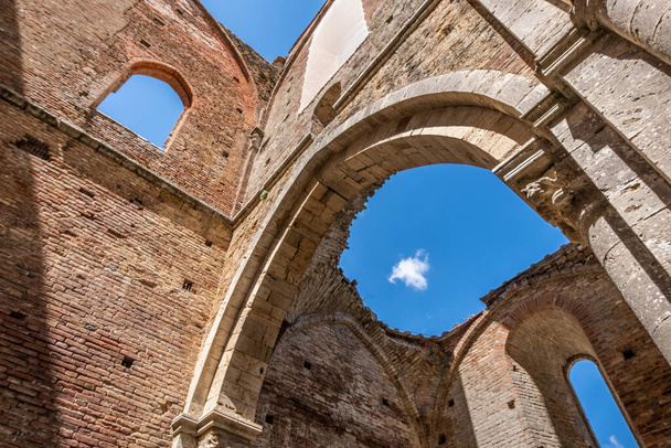 Ancient cathedral with towering walls in Tuscany, Italy. Beautiful view of The Abbey of Saint Galgano, an ancient Cistercian Monastery founded in the province of Siena, region of Tuscany. - 写真・画像