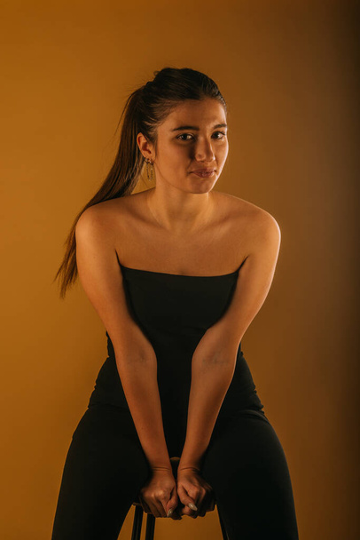 Fashion shoot in studio.. Attractuve girl in black top and black pants looking forward with a slight smile on her face - Photo, Image