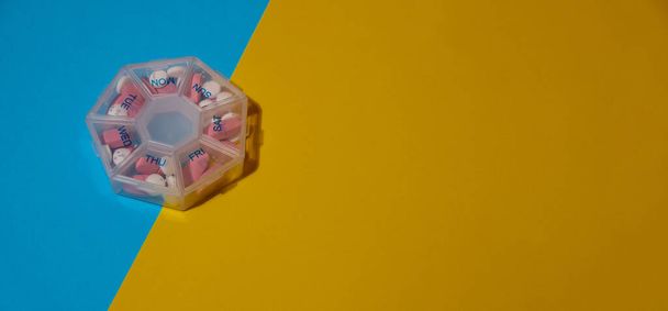Organizer wekelijkse shots medische pil doos met doses tabletten voor dagelijks innemen van medicijnen met witte roze drugs en capsules. Kopieer ruimte Dagelijkse vitamines thuis. Geneesmiddelen dieetsupplementen, immuniteit - Foto, afbeelding