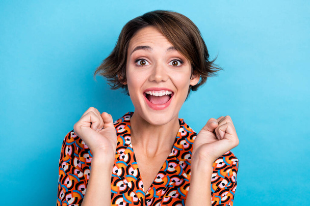Portrait of overjoyed cheerful lady raise fists attainment luck isolated on blue color background. - 写真・画像
