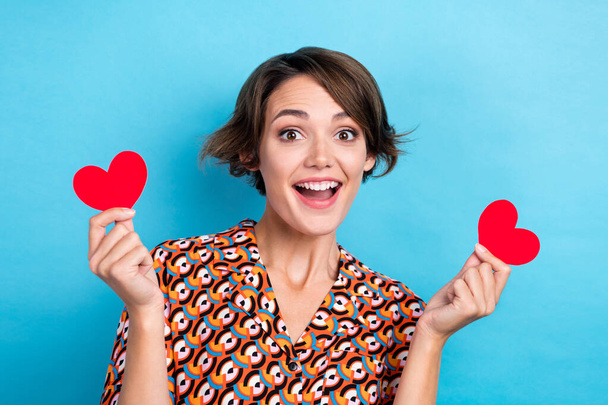 Photo of excited funny woman wear print blouse holding two small red hearts isolated blue color background. - Фото, зображення