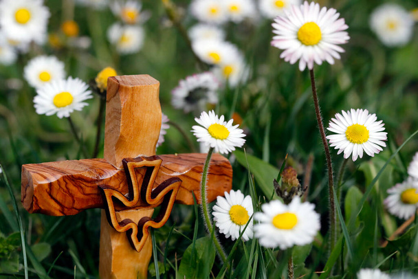 Drewniany krzyż na trawie z kwiatami. Symbol religijny.  - Zdjęcie, obraz