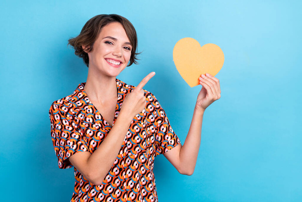 Foto van zoete schattige dame gekleed print shirt stijgende wijzende vinger hart glimlachend geïsoleerde blauwe kleur achtergrond. - Foto, afbeelding