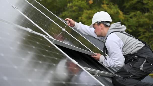 家の屋根の上に太陽光発電パネルをマウントする人技術者。六角キーの助けを借りて太陽電池モジュールシステムをインストールヘルメットのエンジニア。代替的再生可能エネルギーの概念. - 映像、動画