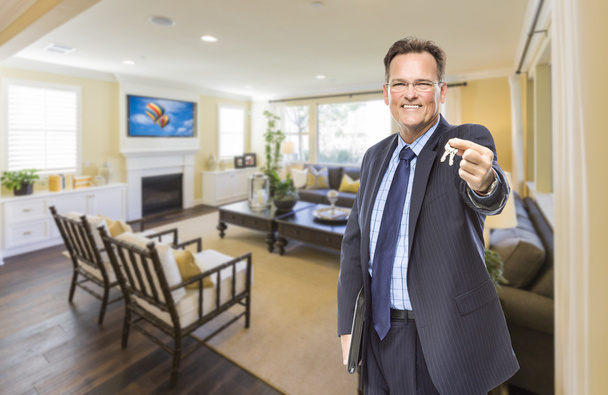 Agente de bienes raíces masculino sosteniendo llaves en la sala de estar hermosa
 - Foto, imagen