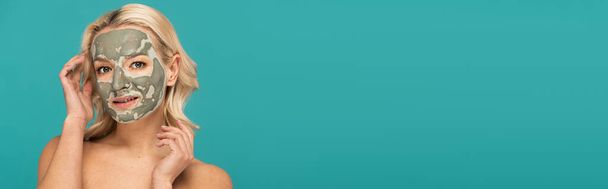 blonde woman with face mask looking at camera isolated on turquoise, banner  - Foto, immagini