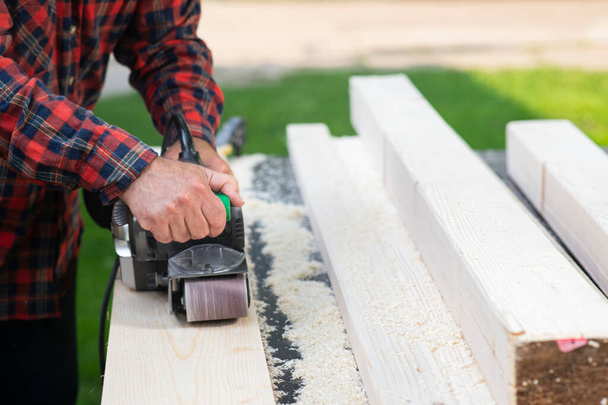 Men working with sanding belt on wooden board outdoors - Foto, Imagem