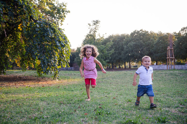 Brat i siostra bawią się razem w parku na świeżym powietrzu w letni dzień - Zdjęcie, obraz